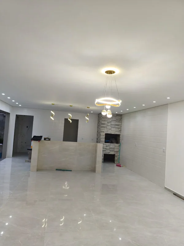 Ambiente residencial em acabamento com lustre, pendentes e spots acesos
