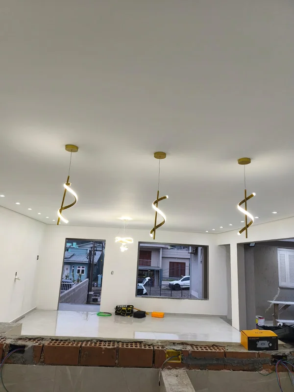 Três pendentes dourados de LED em espiral acesos sobre uma bancada