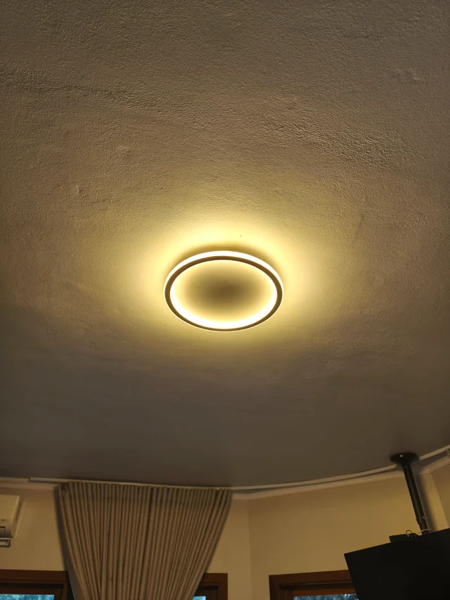 Plafon circular aceso com luz quente no teto de uma sala.