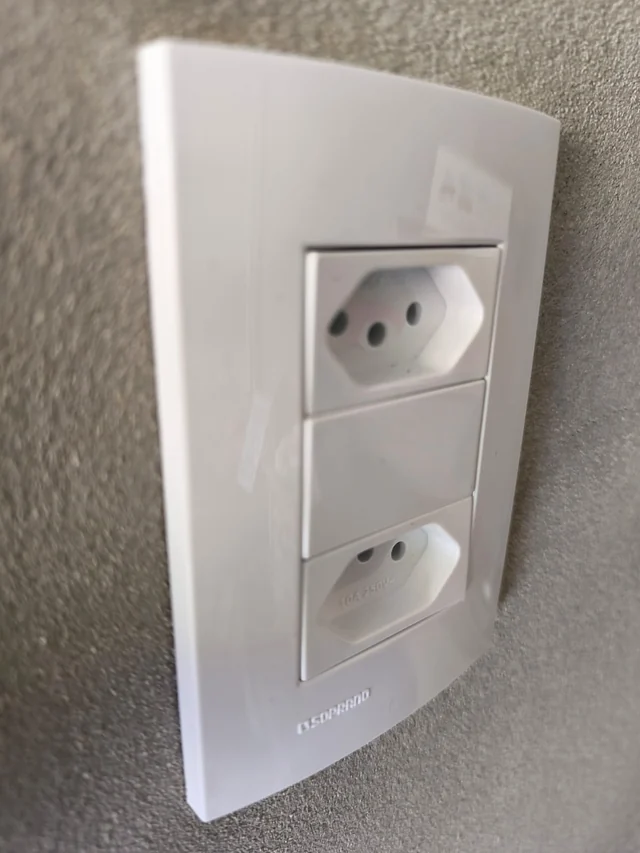 Tomada dupla branca instalada em parede texturizada.
