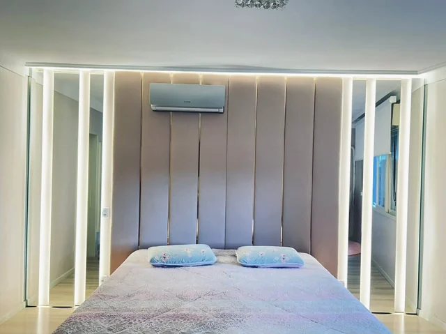 Iluminação linear em torno da cabeceira de uma cama.